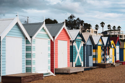 Beach huts by buildings against sky