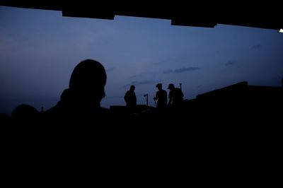 Silhouette men on field at dusk