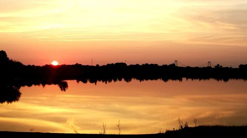 Scenic view of river with orange sky reflection at sunset