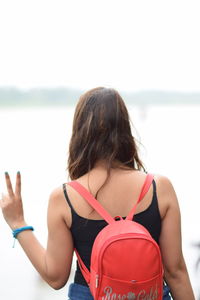 Rear view of woman on beach against sky