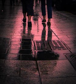 Low section of man standing on wet sidewalk during rainy season