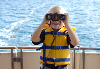 Portrait of boy with binoculars in boat on sea