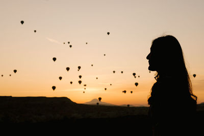 Silhouette woman on land against sky during sunset