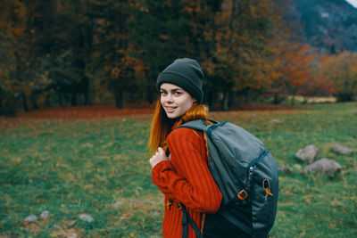 Young woman standing by tree during autumn