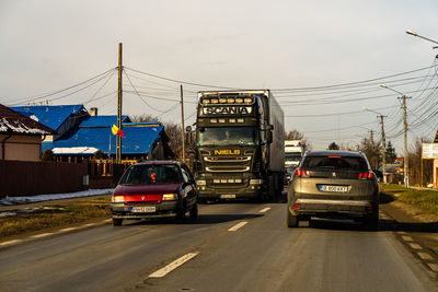 Cars on street in city against sky