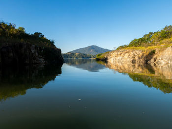 Scenic view of lake and mountains against clear blue sky