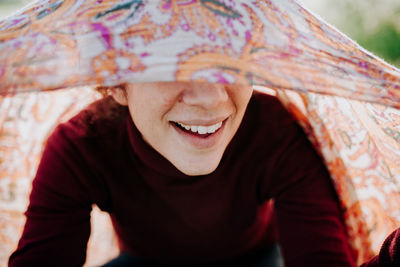 Close-up of smiling woman wearing scarf while sitting outdoors