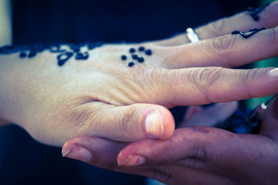 Cropped image of woman with henna tattoo touching friend hand