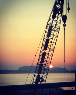 Silhouette of crane against sky during sunset