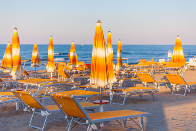 Chairs and tables at beach against sky