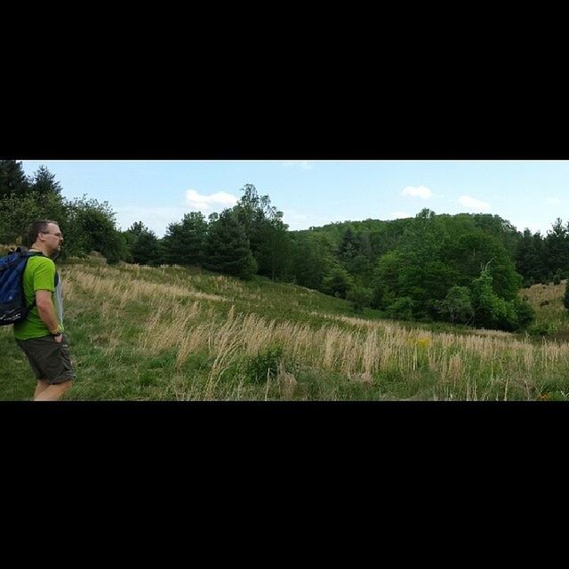 SIDE VIEW OF MAN STANDING ON GRASSY FIELD