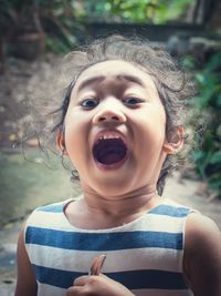 Close-up of girl with mouth open holding spoon while standing outdoors