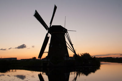 Traditional windmill against sky during sunset