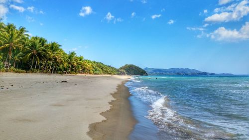 Scenic view of beach against cloudy sky