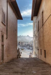 Empty alley amidst buildings in city against sky