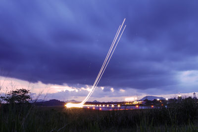 Low angle view of illuminated vapor trail against sky at night
