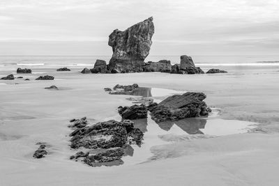 Rock formation on beach against sky