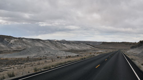 Road leading towards mountains against sky