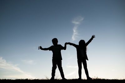 Low angle view of silhouette people standing on field against sky