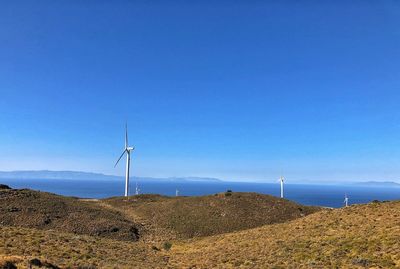 Wind turbines on land against clear blue sky