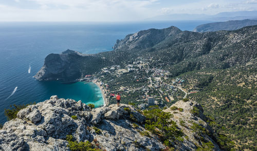 Man traveller at the top of falcon sokol mountain enjoying novyi svit town below. crimea