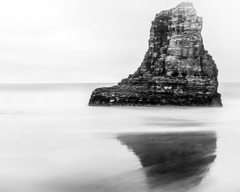 Rock formation in sea against sky