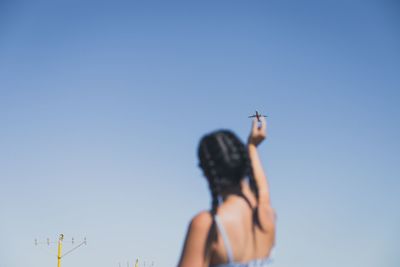 Low angle view of woman standing against clear blue sky