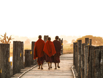 Rear view of people walking on footpath against sky