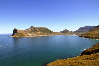 Scenic view of sea and mountains against clear blue sky