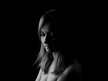 Close-up portrait of young woman against black background