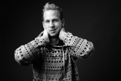 Portrait of young man standing against black background