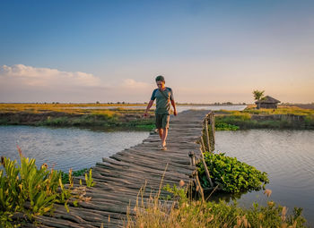 Man standing by lake against sky