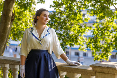 Portrait of young woman standing against trees