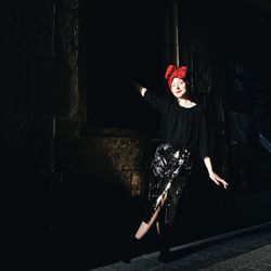 Full length portrait of young woman standing against wall