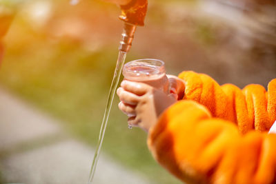 Faceless child fill the glass with water in water tap outdoor person