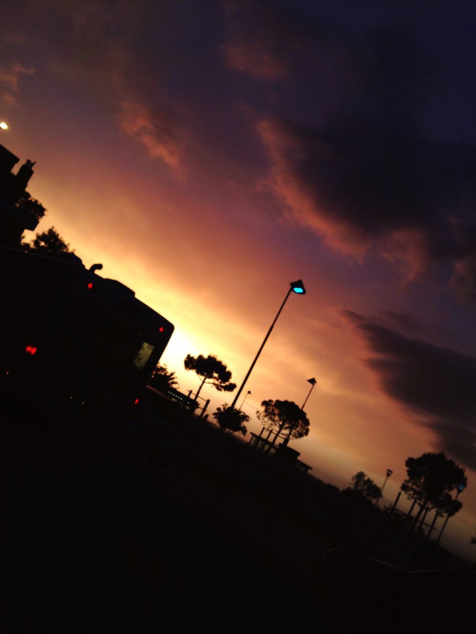 silhouette, sky, low angle view, sunset, cloud - sky, street light, cloudy, tree, dusk, cloud, nature, beauty in nature, dramatic sky, palm tree, overcast, tranquility, weather, outdoors, scenics, lighting equipment