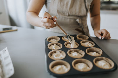 Woman in kitchen preparing cupcakes