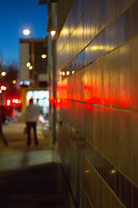 Rear view of person walking on illuminated street at night