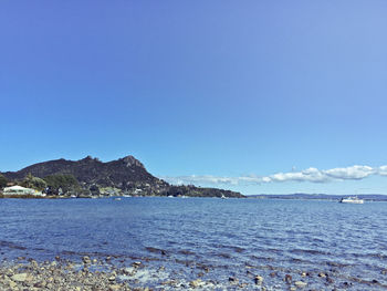 View of calm blue sea against mountain range