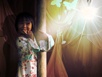 Girl looking away while standing in illuminated room