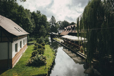 Panoramic view of canal amidst trees and buildings against sky