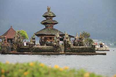 Traditional building by lake against sky