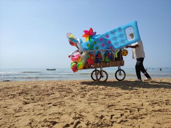 Man with toy on beach against clear sky