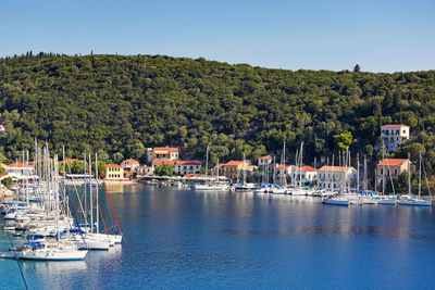 Sailboats moored on river by trees against sky