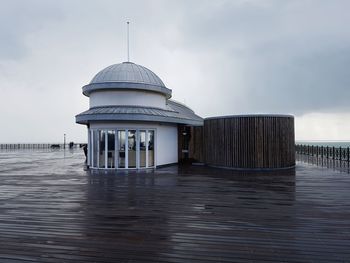 Gazebo on pier against cloudy sky