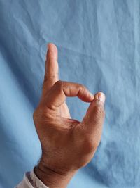 Close-up of human hand against blue wall