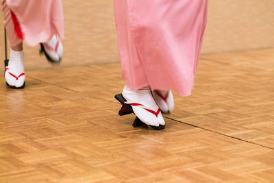 Low section of women standing on hardwood floor