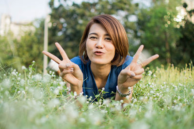 Portrait of woman gesturing peace sign on field