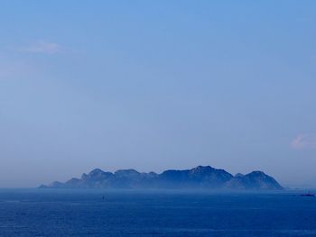 Scenic view of sea and mountains against clear blue sky