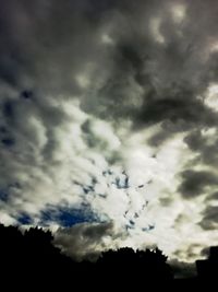 Low angle view of silhouette trees against dramatic sky